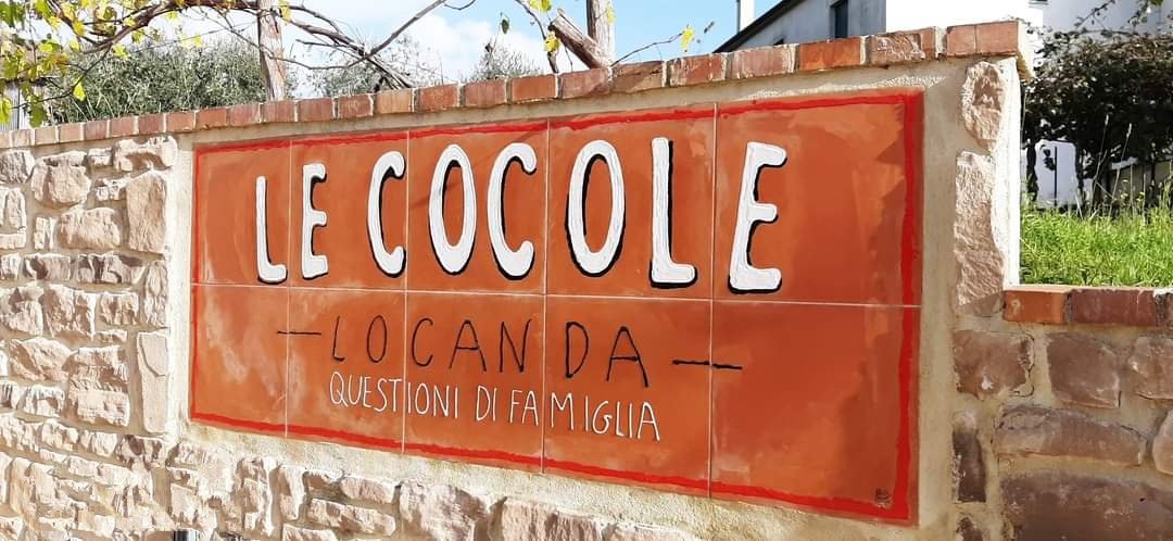 L'insegna dipinta a mano di Locanda Le Cocole, su un muro di pietra nella campagna cilentana